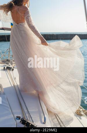 Beautiful Bride hält das Kleid auf dem Deck des yacht Stockfoto