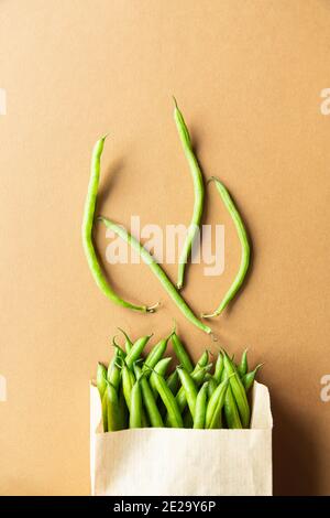 Grüne Bohnen oder Kidney Beans in einem Bastelsack auf braunem Hintergrund. Ernten Sie gesunde Bio-Lebensmittel Stockfoto