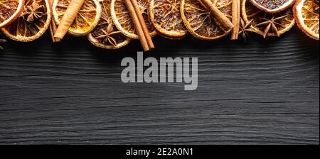 Schwarzer Holzhintergrund mit getrockneten Orangen, Zimt und Anissternen. Von oben aufgenommen. Hintergrund und Textur. Stockfoto