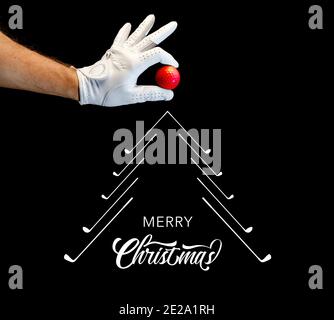 Der Spieler trägt einen Golfhandschuh und hält einen Golfball in den Fingern. Unter der Hand ein grafischer weihnachtsbaum von Golfschlägern mit den Worten Merry christ gemacht Stockfoto