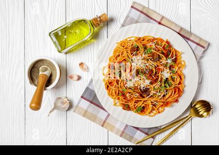 Pasta Spaghetti alla norma auf einem weißen Teller auf einem weißen Holztisch mit Zutaten, italienische Küche, horizontale Ansicht von oben, flache Laie Stockfoto