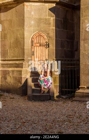 Ein Mädchen sitzt auf einer Treppe in der Nähe der Schwarzen Kirche In Brasov Stockfoto