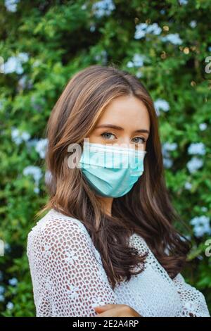 Flacher Fokus einer erwachsenen Brünette weiblich trägt eine Spitze shirt mit Gesichtsbesetzer und posiert im Freien Stockfoto