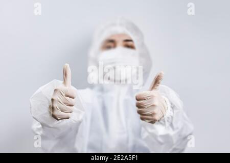 Porträt eines Arztes, der gegen das Coronavirus kämpft. Eine Krankenschwester in medizinischer Schutzkleidung, die die Kamera betrachtet. Mitarbeiter im Gesundheitswesen zeigt Daumen nach oben Stockfoto