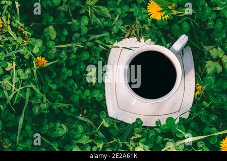 Weiße Tasse mit schwarzem Kaffee auf der Wiese mit grünen Klee Top View closeup Stockfoto