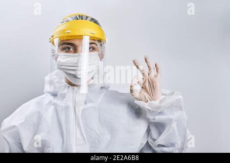 Porträt eines Arztes, der gegen das Coronavirus kämpft. Eine Krankenschwester in medizinischer Schutzkleidung, die die Kamera betrachtet. Gesundheitshelfer zeigt OK oder gut Stockfoto