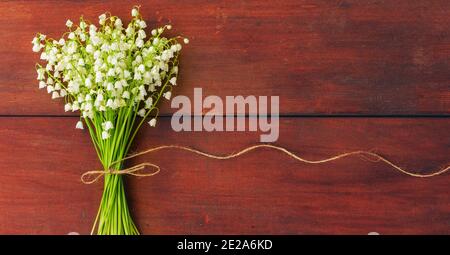 Weiße Blüten Maiglöckchen auf braunem Holz. Kopieren Sie Platz. Freier Platz für Text Stockfoto