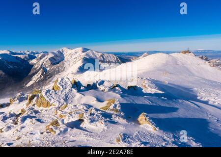 Blick von Kasprowy Wierch auf Kiefernwald mit Winterüberzug im Tal. Schneebedeckte Berggipfel der Tatra, Bukowina Tatrzanska, Polen Stockfoto