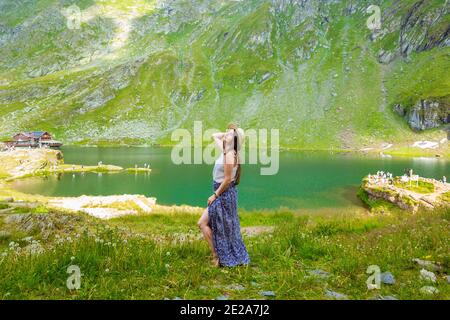 Eine schöne Frau in einem Kleid und Hut steht in der Nähe Des Balea-Sees Stockfoto