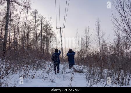 (210113) -- MOHE, 13. Januar 2021 (Xinhua) -- Lyu Jiansheng (R) und Wang Shaoting führen Stromlinienpatrouille im Wald in der Nähe des Dorfes Beiji der Stadt Mohe, nordöstlich der Provinz Heilongjiang, 12. Januar 2021. Das Dorf Beiji in Mohe City, der nördlichsten Stadt Chinas, konnte sich nur noch vor 2007 auf kleine Dieselgeneratoren zur Stromversorgung verlassen. Nach dem Anschluss an das Staatsnetz, Beiji Village Einrichtung der nördlichsten Stromversorgung in China, die Beiji Power Supply Station. Direktor Lyu Jiansheng und Zählerleser Wang Shaoting sind die einzigen zwei Mitarbeiter der Station, die ist Stockfoto