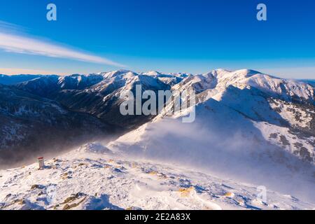 Blick von Kasprowy Wierch auf Kiefernwald mit Winterüberzug im Tal. Schneebedeckte Berggipfel der Tatra, Bukowina Tatrzanska, Polen Stockfoto