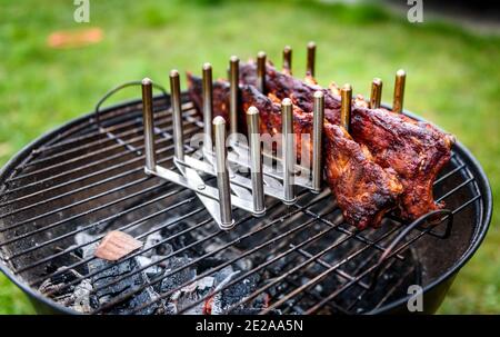Baby zurück Spare Ribs Braten auf BBQ Grill Kugelgrill. Hausgemachte Schweinerippchen auf einem Grill mit geringe und langsame Methode. Grillen draußen in der Natur bei Fami Stockfoto