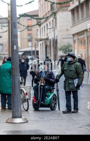 terni,italien Januar 13 2021:Mann mit motorisiertem Rollstuhl und Freunde sprechen Im Stadtzentrum Stockfoto
