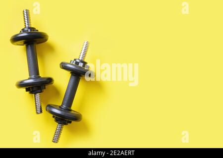 Sport schwarze Kurzhanteln auf gelbem Hintergrund. Ansicht von oben, Platz kopieren. Stockfoto