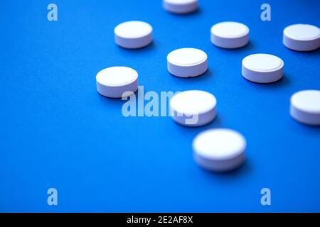 Set von weißen Pillen auf blauem Hintergrund. Pillen Hintergrund. Weiße Tabletten auf blauem Hintergrund Stockfoto