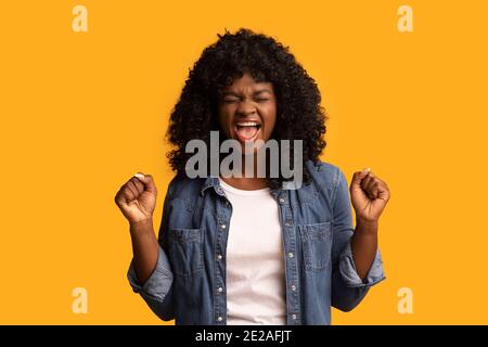 Emotionale afroamerikanische Frau, die die Fäuste hochhebt und schreit Stockfoto