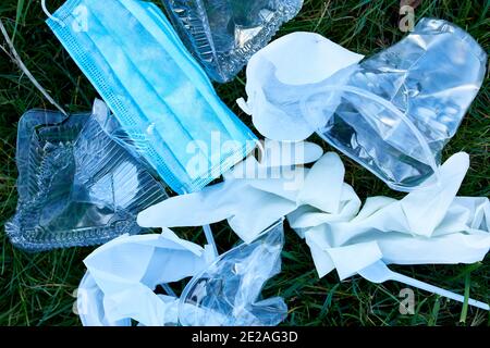 Piile verstreuten Müll auf einem Hintergrund von grünem Gras, um verstreuten Kunststoff, Schutzmaske, Handschuhe, Abfall während Coronavirus Pandemie, Speichern Stockfoto