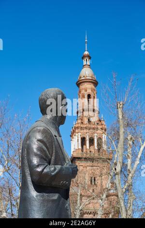 Staute von Anibal Gonzalez, der Architekt der Plaza de Espagne, Sevilla, Spanien an einem Wintertag mit klarem blauen Himmel, mit Blick auf das Gebäude Stockfoto