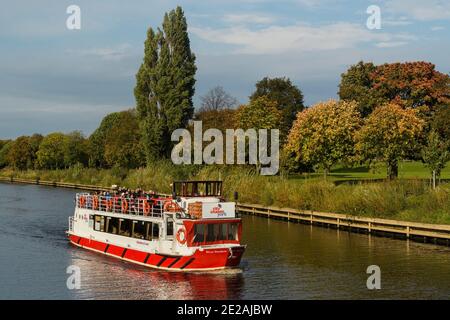 Passagiere, die auf dem Oberdeck sitzen, genießen eine sonnige Herbstkreuzfahrt auf dem malerischen Fluss Ouse an Bord eines City Cruises Bootes - York, Yorkshire, England, UK. Stockfoto