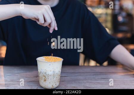 Barista streut gesalzenes Eigelb-Pulver auf Eistschokolade ein Café Stockfoto