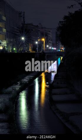 Nachtansicht eines langsamen Flusses, der mehrere Straßenlaternen reflektiert In einem ruhigen Teil des Zentrums von Tokio Stockfoto