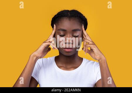 Afrikanisches Weibliches Denken Massierenden Tempel Mit Geschlossenen Augen, Gelber Hintergrund Stockfoto