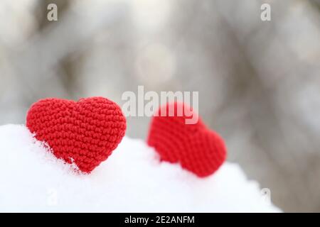 Valentine Herzen im Winterwald im Sonnenlicht. Zwei rote gestrickte Herzen auf Schnee, Symbol der romantischen Liebe, Hintergrund für den Urlaub Stockfoto