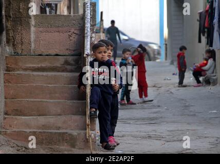 (210113) -- GAZA, 13. Januar 2021 (Xinhua) -- Kinder spielen vor ihren Häusern im Al-Shati Flüchtlingslager in Gaza-Stadt, 11. Januar 2021. Am 24. August 2020 verkündeten die von der Hamas geführten Behörden in Gaza die ersten vier Fälle von COVID-19 und verhängten eine Reihe restriktiver Maßnahmen, um die Ausbreitung des Virus einzudämmen. Seitdem sind alle Kirchen, Moscheen, Schulen, Märkte und private Institutionen geschlossen und öffentliche Versammlungen verboten. ZUM THEMA "Feature: Palästinensische Flüchtlingsstudenten hoffen auf volle Bildung in der Zeit nach der Pandemie" (Foto: Rizek Abdeljawad/Xinhua) Stockfoto