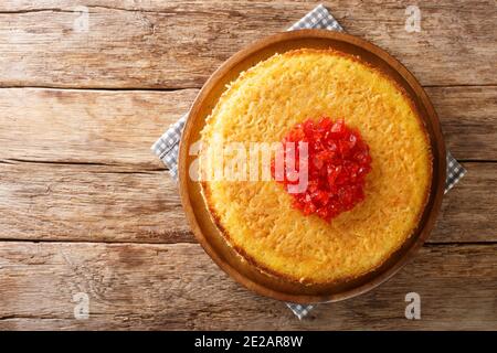 Iranischer Tahchin-Reiskuchen mit Huhn in der Nähe auf dem Teller auf dem Tisch. Horizontale Draufsicht von oben Stockfoto