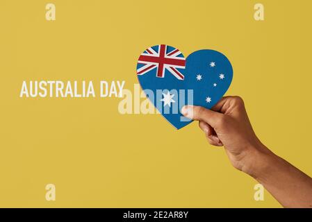 Nahaufnahme der Hand eines Mannes, der eine australische Flagge in Form eines Herzens hält, mit Ausschnitten aus Papier in verschiedenen Farben und dem Text australi Stockfoto