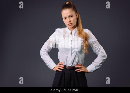 Serious junge Geschäftsfrau in weißem Hemd posiert auf grauem Hintergrund mit leerem Raum. Stockfoto