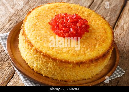 Iranischer Tahchin-Reiskuchen mit Huhn in der Nähe auf dem Teller auf dem Tisch. Horizontal Stockfoto