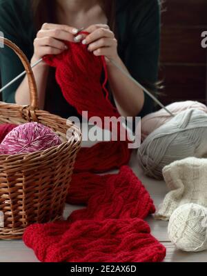 Junge Frau strickt roten Schalldämpfer zu Hause in der Freizeit, Fancywork und Nadelarbeit Konzept, Nahaufnahme der Handarbeit, Kopierraum, von oben Ansicht von oben Stockfoto