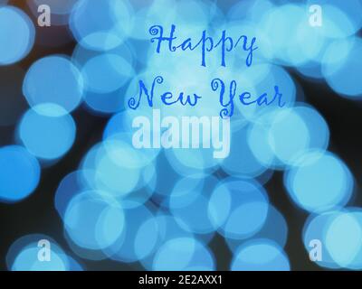 Frohes neues Jahr, blaue Inschrift auf unfokussierter Bokeh-Kulisse, dominante blaue Blasen im schwarzen Hintergrund. Grußkarte mit Text. Festliches Dessin. Stockfoto