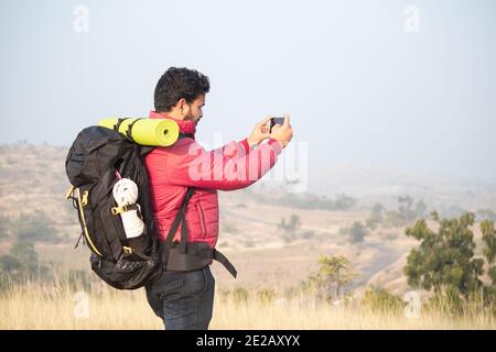 Junge Reisende mit Rucksack fotografieren Landschaft mit Mobile Kamera auf dem Berg - Konzept des Reisens und Abenteuer Fotografie während tr Stockfoto