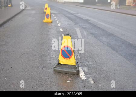 Nahaufnahme der gelben Warnung, keine wartenden Verkehrskegel, auf asphaltierten Straße, die den Verkehr an einem nebligen Tag nicht zum Parken am Straßenrand leitet Stockfoto