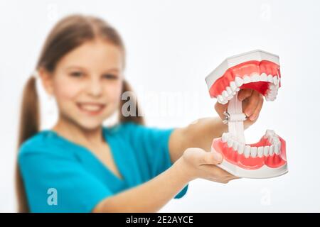 Nettes Mädchen spielen Zahnarzt, hält ein Spielzeug Modell Kiefer für Studie. Kinderhobby und zukünftige medizinische Beschäftigung Stockfoto