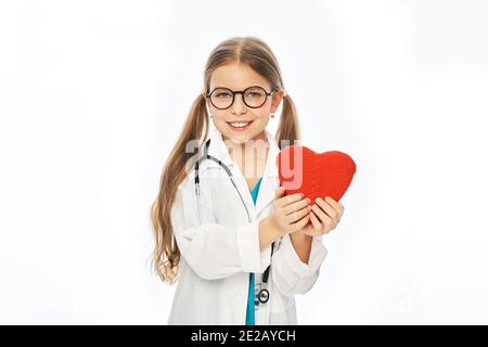 Kleines Mädchen mit Brille und medizinischem Mantel, das Herzform hält. Medizinische Betreuung und Betreuung von Kindern, Pädiatrie Stockfoto