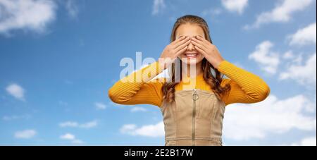 Lächelndes Teenager-Mädchen, das ihre Augen über dem Himmel schließt Stockfoto