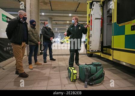 Metropolitan Police Officers in einfacher Kleidung werden Ausrüstung neben einem Krankenwagen von einem Mitglied des London Ambulance Service (LAS) im Wembley Stadium, Nord-London gezeigt, wo Offiziere der Metropolitan Police ausgebildet werden, um dem LAS zu helfen. Stockfoto
