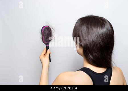 Das Mädchen hält einen Kamm für Haare mit gefallenen Haaren. Haarausfall, Haarpflege Stockfoto