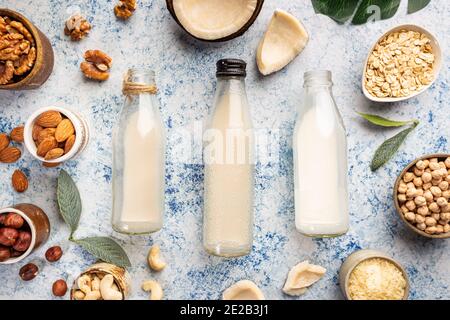 Vegane Milch auf pflanzlicher Basis, nicht milchfrei, in Flaschen und Zutaten auf blauem Hintergrund. Laktosefreier Milchersatz. Draufsicht. Stockfoto