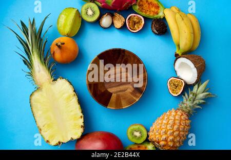 Holzschale und verschiedene exotische Früchte auf blau Stockfoto