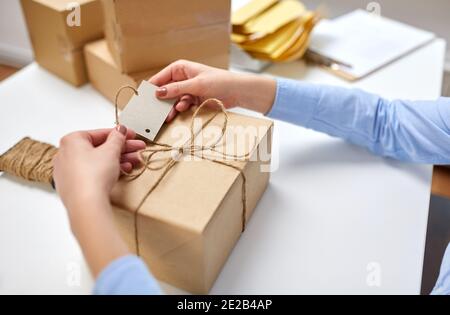 Hände, die Namensschild an Paketkasten bei der Post binden Stockfoto