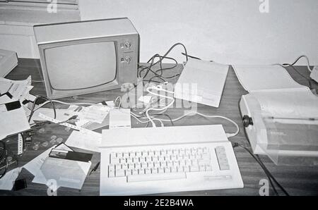 Eine schlampige Arbeitsstation in den 1980er Jahren, mit einem Commodore 64 Computer, der an einen schwarz-weißen Fernseher angeschlossen ist, einem 5 1/4 Zoll Diskettenlaufwerk, einem 300 Baud Modem und einem Punktmatrix-Drucker Stockfoto