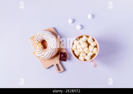 Draufsicht auf Stillleben eines gebissenen Kuchens auf einem kleinen Servierbrett und einer Tasse Kakao mit Marshmallows. Selektiver Fokus, horizontale Ausrichtung. Stockfoto