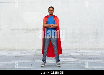 indischer Mann im roten Superhelden Umhang mit gekreuzten Armen Stockfoto