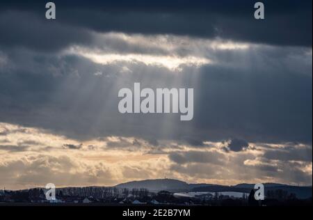 13. Januar 2021, Hessen, Groß-Umstadt: Die Wolken über den ersten Hügeln des nördlichen Odenwaldes lassen Sonnenstrahlen durch die teilweise schneebedeckte Landschaft. Foto: Frank Rumpenhorst/dpa Stockfoto