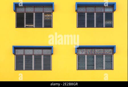 4 Fenster mit gelbem Hintergrund und blau lackierten Fenstern Stockfoto