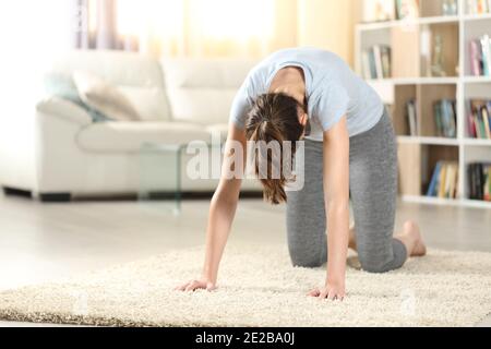 Frau praktiziert Yoga Katze Pose auf dem Boden zu Hause Stockfoto